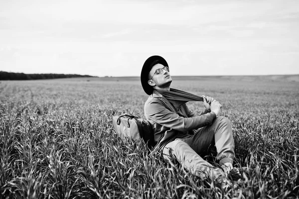 Gözlük, kahverengi ceket ve şapka çanta ile şık adam yeşil sahada poz verdi..