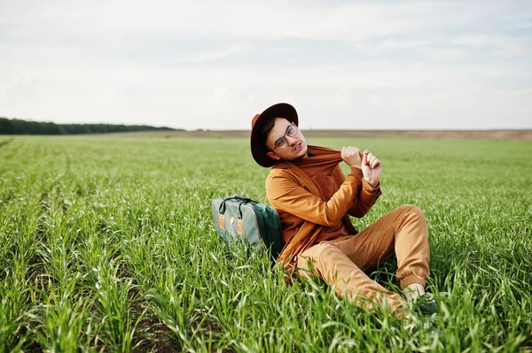 Gözlük, kahverengi ceket ve şapka çanta ile şık adam yeşil sahada poz verdi..