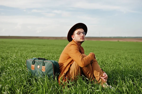 Gözlük, kahverengi ceket ve şapka çanta ile şık adam yeşil sahada poz verdi..