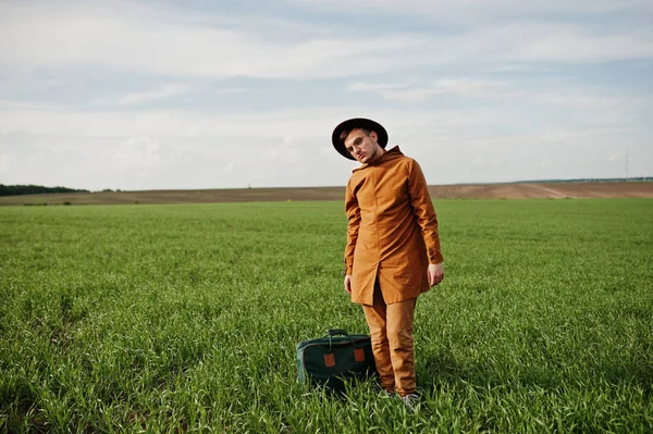 Gözlük, kahverengi ceket ve şapka çanta ile şık adam yeşil sahada poz verdi..
