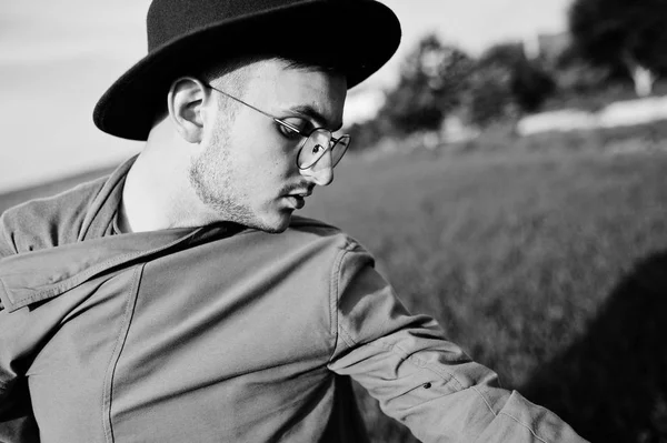 Şık adam gözlük, kahverengi ceket ve şapka yeşil sahada poz verdi..