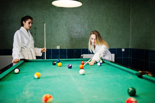 Beyaz bornoz iki seksi kızlar havuz bilardo oynamak.
