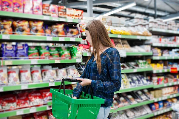 购物的女人看着超市的架子 一个年轻女孩的肖像在市场商店举行绿色商店篮子 — 图库照片
