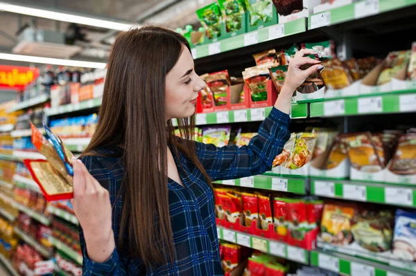 Süpermarket raflarında bakarak kadın alışveriş. Baharat tutan bir pazar mağaza genç bir kızın portresi.