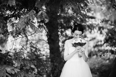 Çarpıcı bir genç gelin holidng portresi ormandaki onu buket. Siyah ve beyaz fotoğraf.