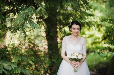 Çarpıcı bir genç gelin holidng portresi ormandaki onu buket.