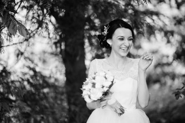 Çarpıcı bir genç gelin holidng portresi ormandaki onu buket. Siyah ve beyaz fotoğraf.