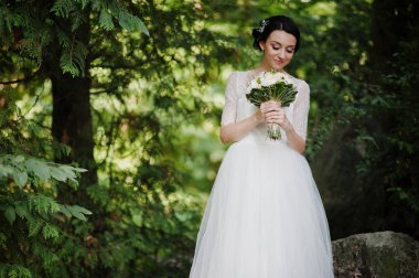 Çarpıcı bir genç gelin holidng portresi ormandaki onu buket.