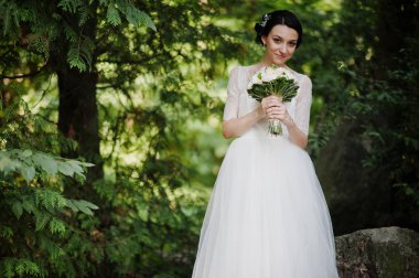 Çarpıcı bir genç gelin holidng portresi ormandaki onu buket.