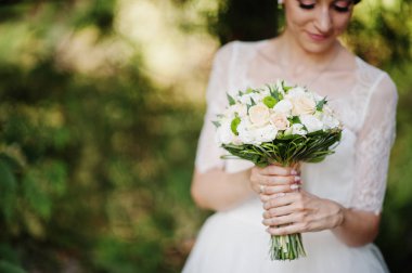 Çarpıcı bir genç gelin holidng portresi yakın çekim ormanda onu buket.