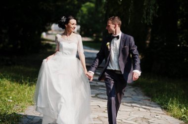 Güzel çift tutuşup düğün ve güneşli günde parkta yürüyüş.