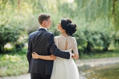 Sarılma ve nehir kenarında açık havada duran muhteşem düğün çifti.