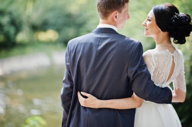 Sarılma ve nehir kenarında açık havada duran muhteşem düğün çifti.