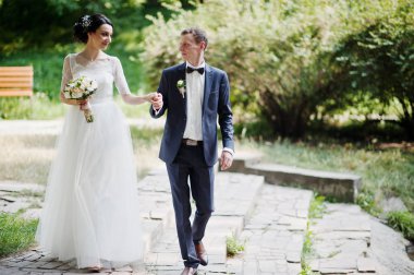 Genç newlyweds güneşli düğün günü parkta yürüyüş.