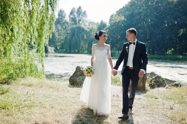 結婚式のカップルを歩くと川の土手にお互いの目を見て — ストック写真