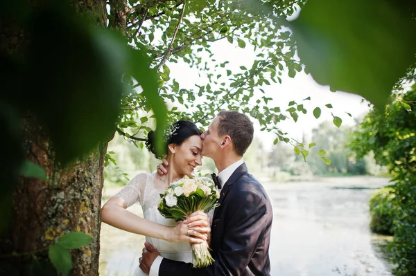新婚夫妇在他们的婚礼当天在湖边或池塘旁边摆着一棵树 — 图库照片