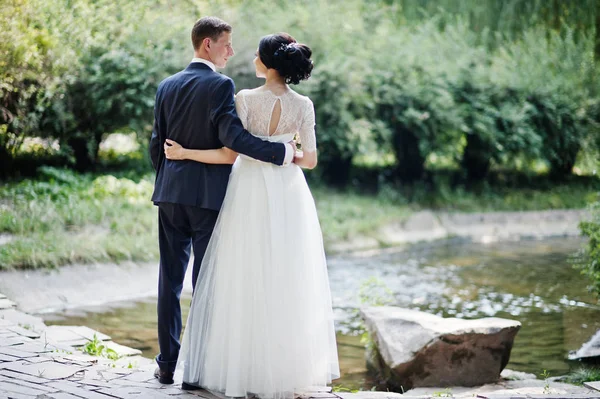 Fantastic wedding couple hugging and standing by the river outdoors.