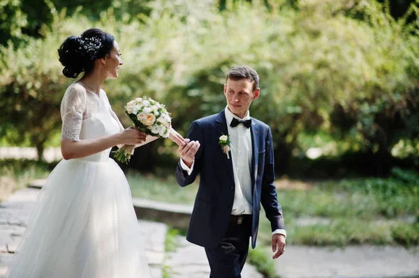 Genç newlyweds güneşli düğün günü parkta yürüyüş.