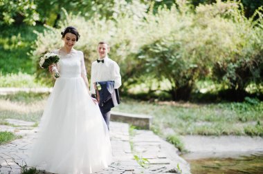 Genç newlyweds güneşli düğün günü parkta yürüyüş.