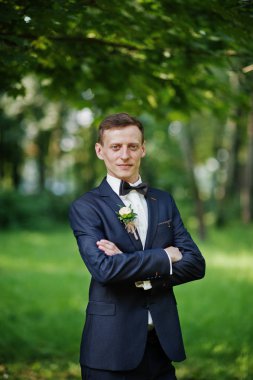 Parkta düğün gününde yalnız poz bir yakışıklı damat portresi.