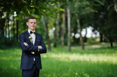 Parkta düğün gününde yalnız poz bir yakışıklı damat portresi.