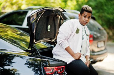 Şık hipster Arap adam adam sokak ve gövdede siyah onun kas araba oturan açık poz verdi. Zengin siyah adam.