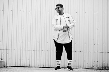Şık hipster Arap adam adam sokakta açık poz verdi. Stil rap şarkıcısı çelik duvara.