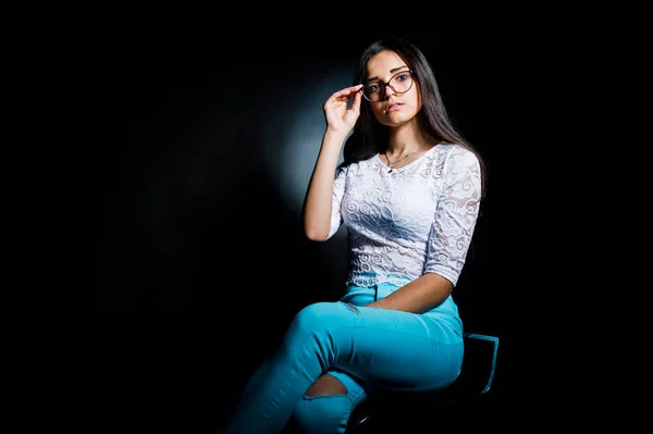 トップと青白の魅力的な若い女性の肖像画は暗闇の中で彼女のメガネで座っているポーズ パンツします — ストック写真