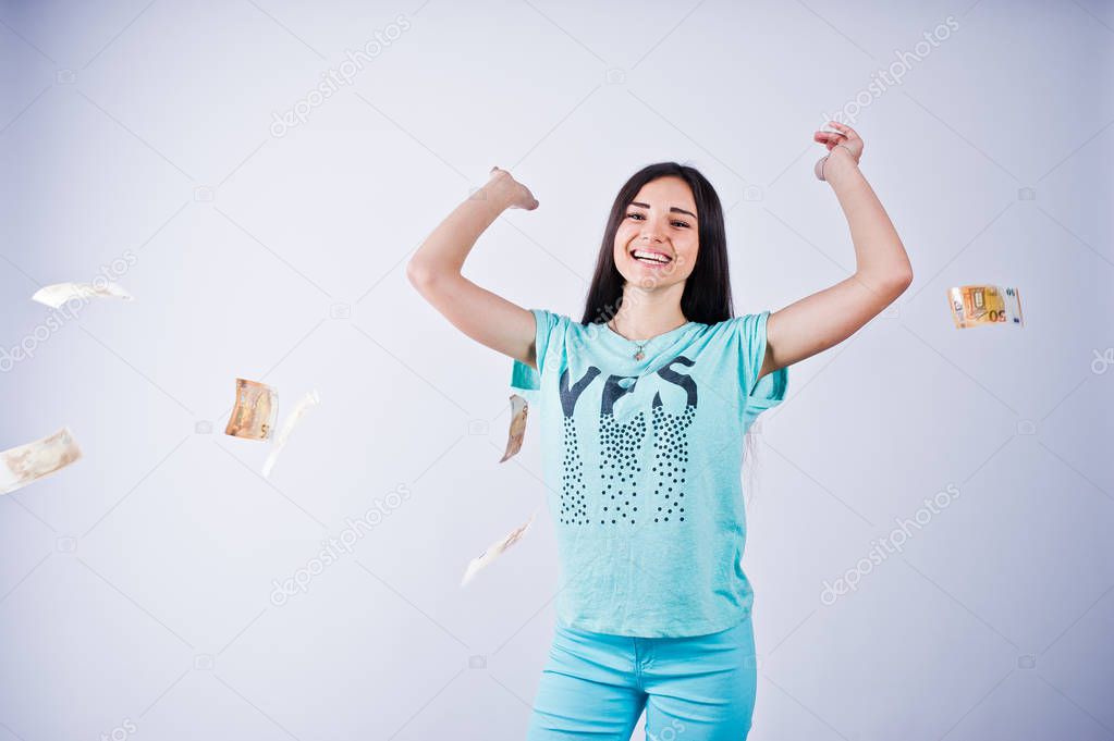 Portrait of an attractive girl in blue or turquoise t-shirt and trousers throwing a lot of money.