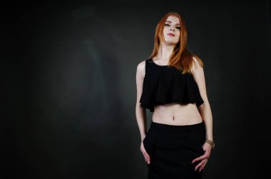 Kızıl saçlı kız yanındaki gri duvar Studio'da poz siyah üst ve siyah etek güzel bir portresi.