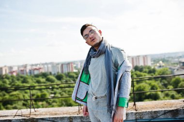 Gri takım elbise, eşarp ve gözlük hayalperest şık maço adam çatıda poz verdi.. 
