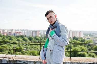 Gri takım elbise, eşarp ve gözlük hayalperest şık maço adam çatıda poz verdi.. 