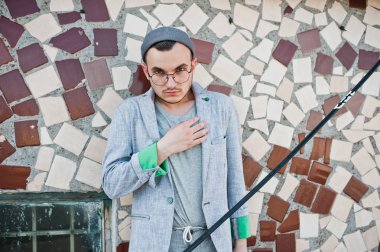 Gri takım elbise, şapka ve gözlük hayalperest şık maço adam çatıda poz verdi.. 