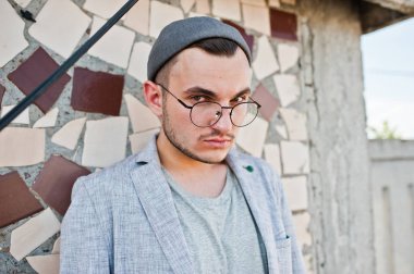 Gri takım elbise, şapka ve gözlük hayalperest şık maço adam çatıda poz verdi.. 