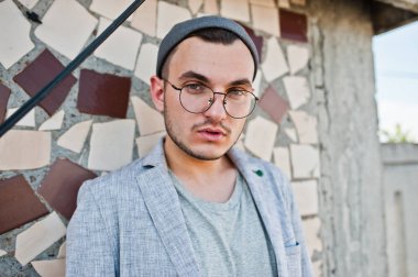 Gri takım elbise, şapka ve gözlük hayalperest şık maço adam çatıda poz verdi.. 