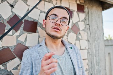 Gri takım elbise, şapka ve gözlük hayalperest şık maço adam çatıda poz verdi.. 