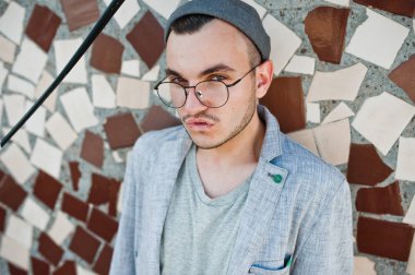 Gri takım elbise, şapka ve gözlük hayalperest şık maço adam çatıda poz verdi.. 