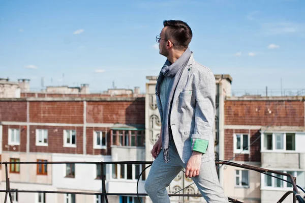 Gri takım elbise, eşarp ve gözlük hayalperest şık maço adam çatıda poz verdi.. 