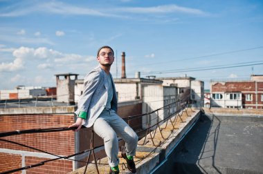 Gri takım elbise, şapka ve gözlük hayalperest şık maço adam çatıda poz verdi.. 