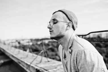 Gri takım elbise, şapka ve gözlük hayalperest şık maço adam çatıda poz verdi.. 