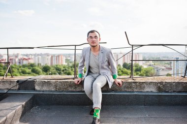 Gri takım elbise, şapka ve gözlük hayalperest şık maço adam çatıda poz verdi.. 
