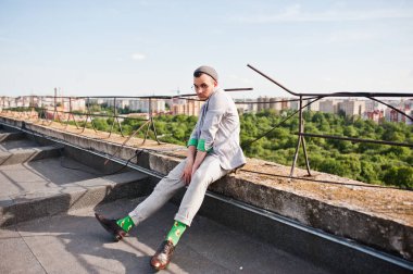 Gri takım elbise, şapka ve gözlük hayalperest şık maço adam çatıda poz verdi.. 