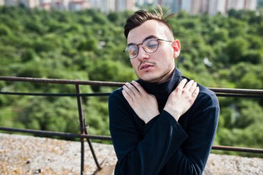 Hayalperest şık maço erkek siyah golf ve gözlük çatıda poz verdi..