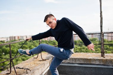 Hayalperest şık maço erkek siyah golf ve gözlük çatıda poz verdi..