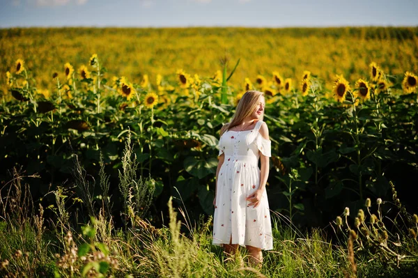 Blonde pregnant mother in sunflowers field. Happy moments of pregnancy.