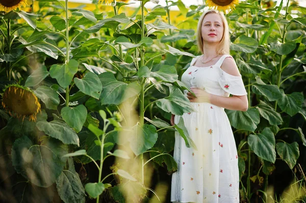 Blonde pregnant mother in sunflowers field. Happy moments of pregnancy.