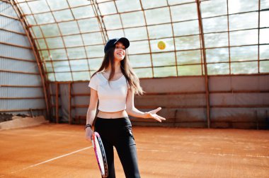 Tenis kortunda tenis raketi ile çalan genç sportif kız.