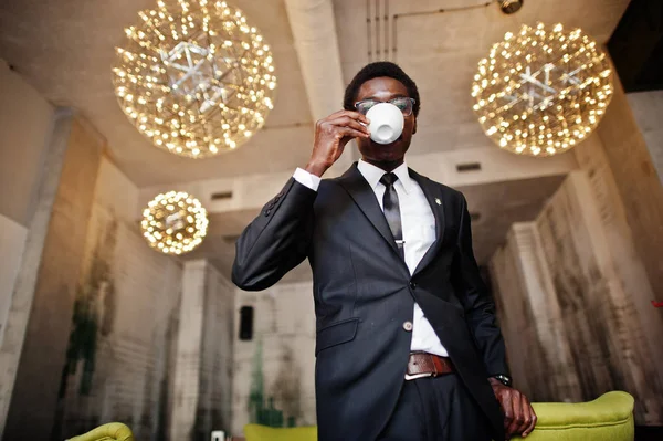 ビジネスのアフリカ系アメリカ人着用黒のスーツとメガネのオフィスで作業日の前に朝のコーヒーを飲む — ストック写真