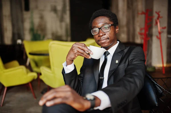 Business african american man wear on black suit and glasses at office, drinking morning coffee before work day.