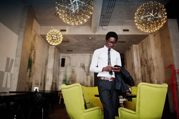 Business african american man wear on black suit and glasses at office looking on mobile phone.